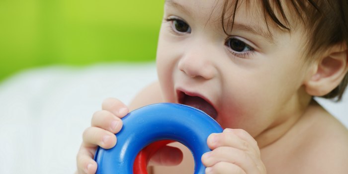 A kid bitting a plastic pool toy while playing